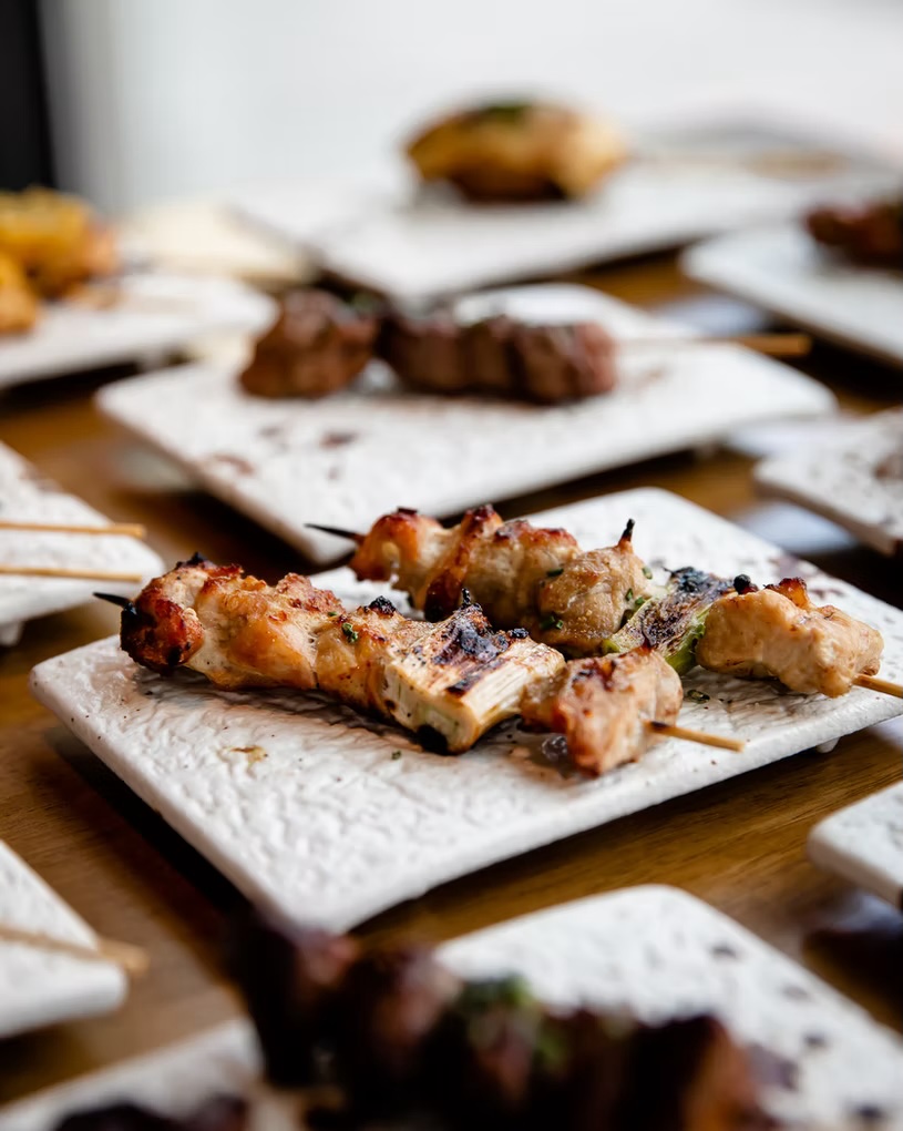 Charcoal-grilled chicken skewers on textured white stone plates