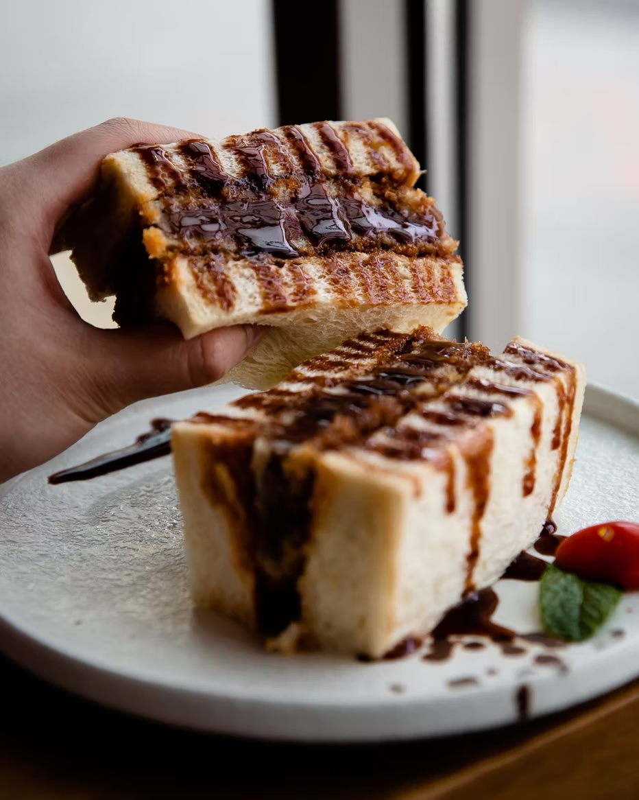 Grilled dessert toast layered with chocolate, lifted above the plate