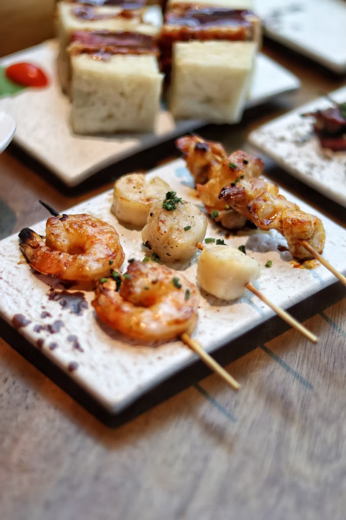 Grilled prawn and scallop skewers on a white stone plate
