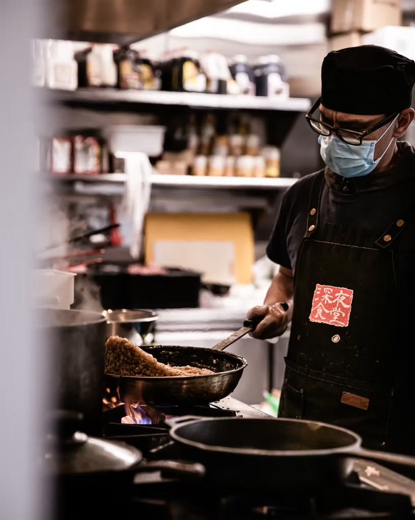 Chef in the Shinya Shokudo apron working the pans in the kitchen