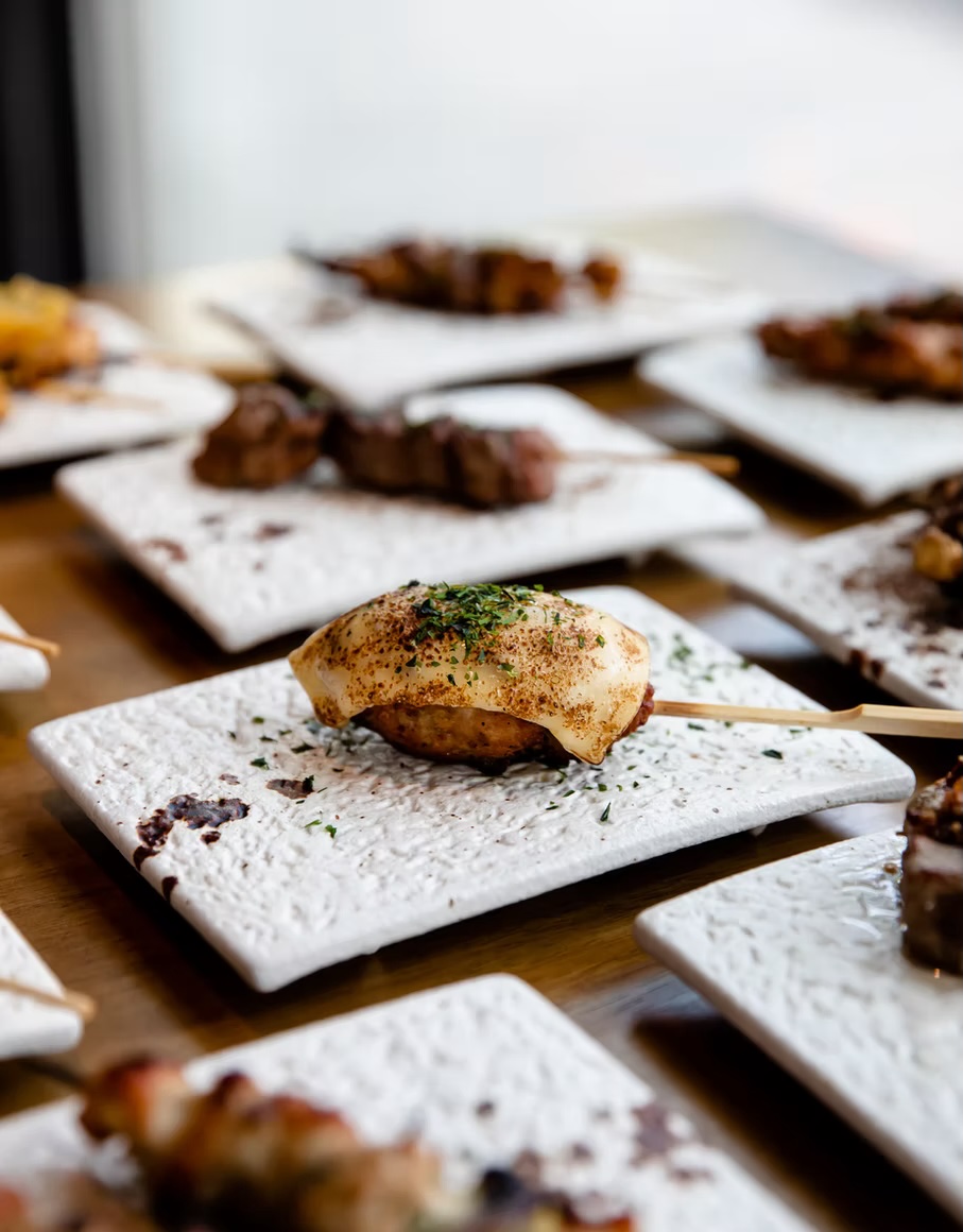 Charcoal-grilled skewer resting on a textured white ceramic plate