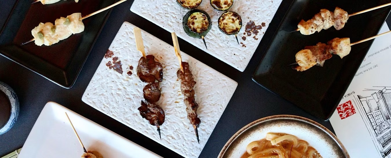 Skewer omakase spread across white stone plates, seen from above