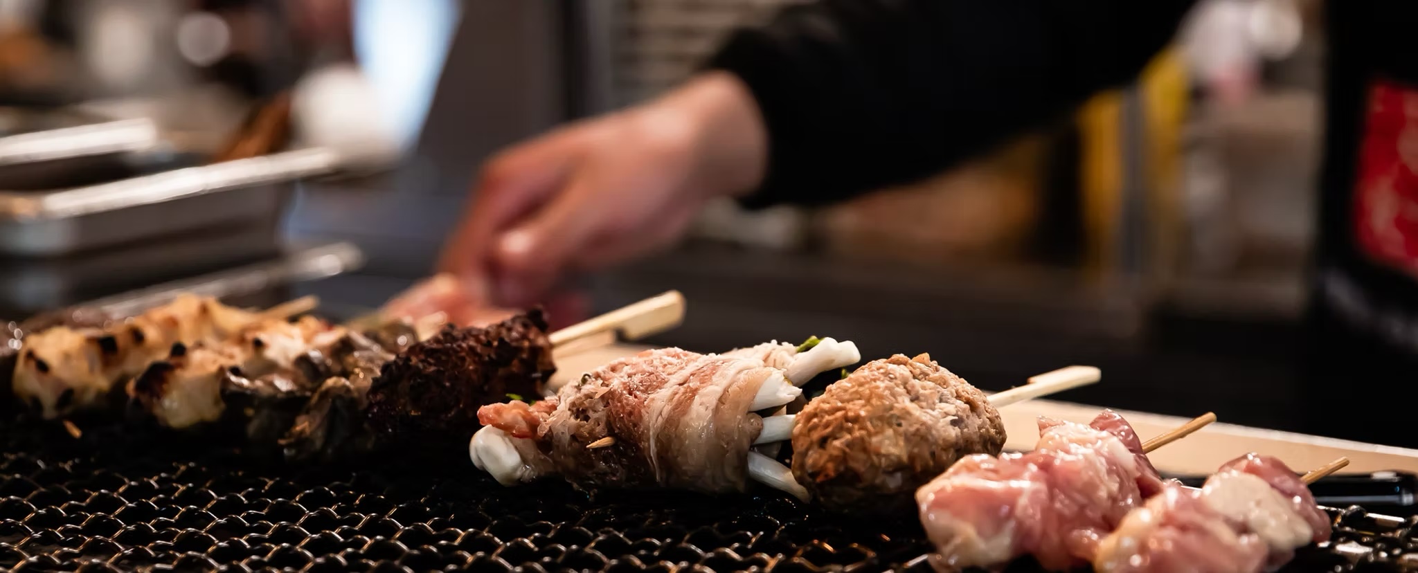 Rows of chicken skewers searing over glowing charcoal