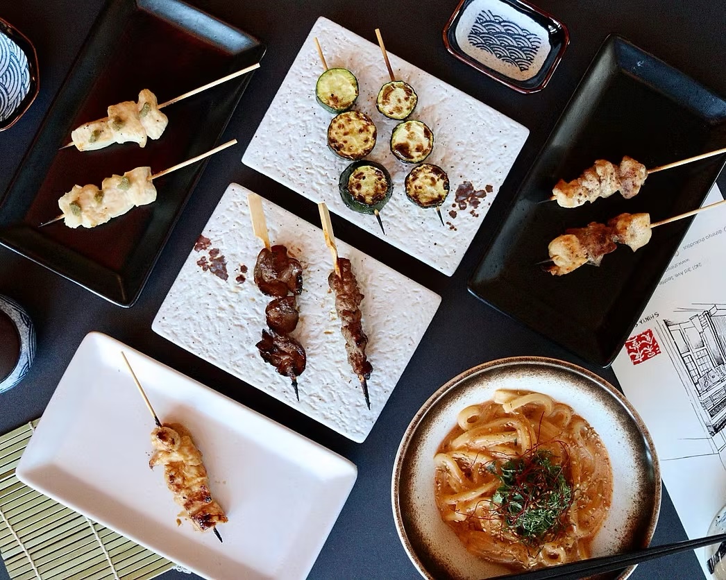 Overhead view of assorted yakitori skewers on ceramic plates